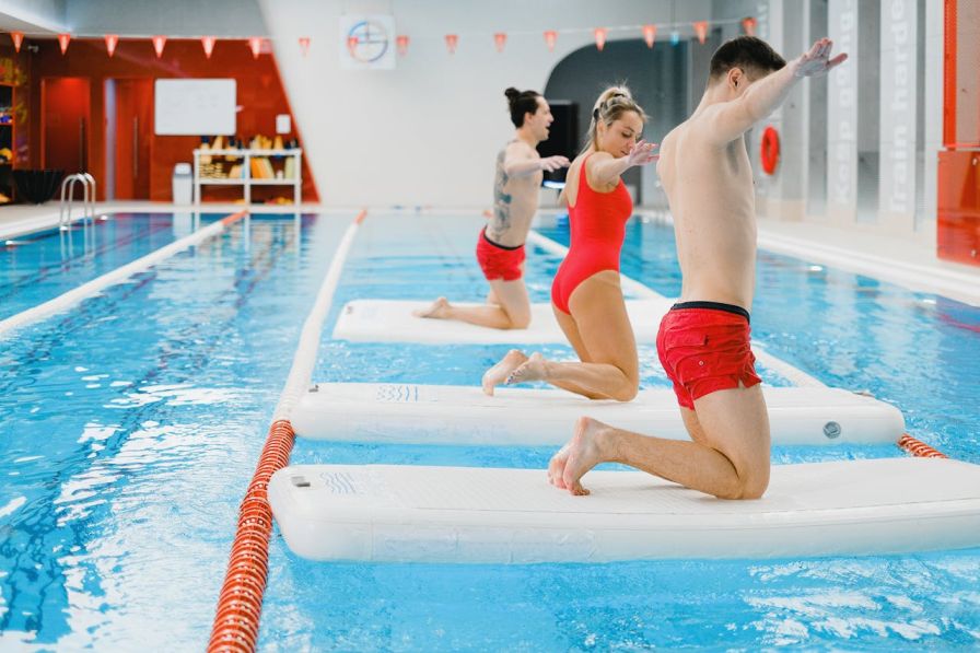 Supportive swim instructor building trust with an adult beginner. 